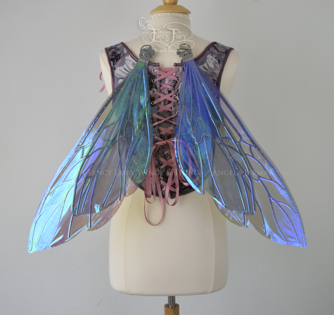 Large fairy wings similar in shape to wasp wings, are iridescent violet / blue with silver veins, back view, in resting position