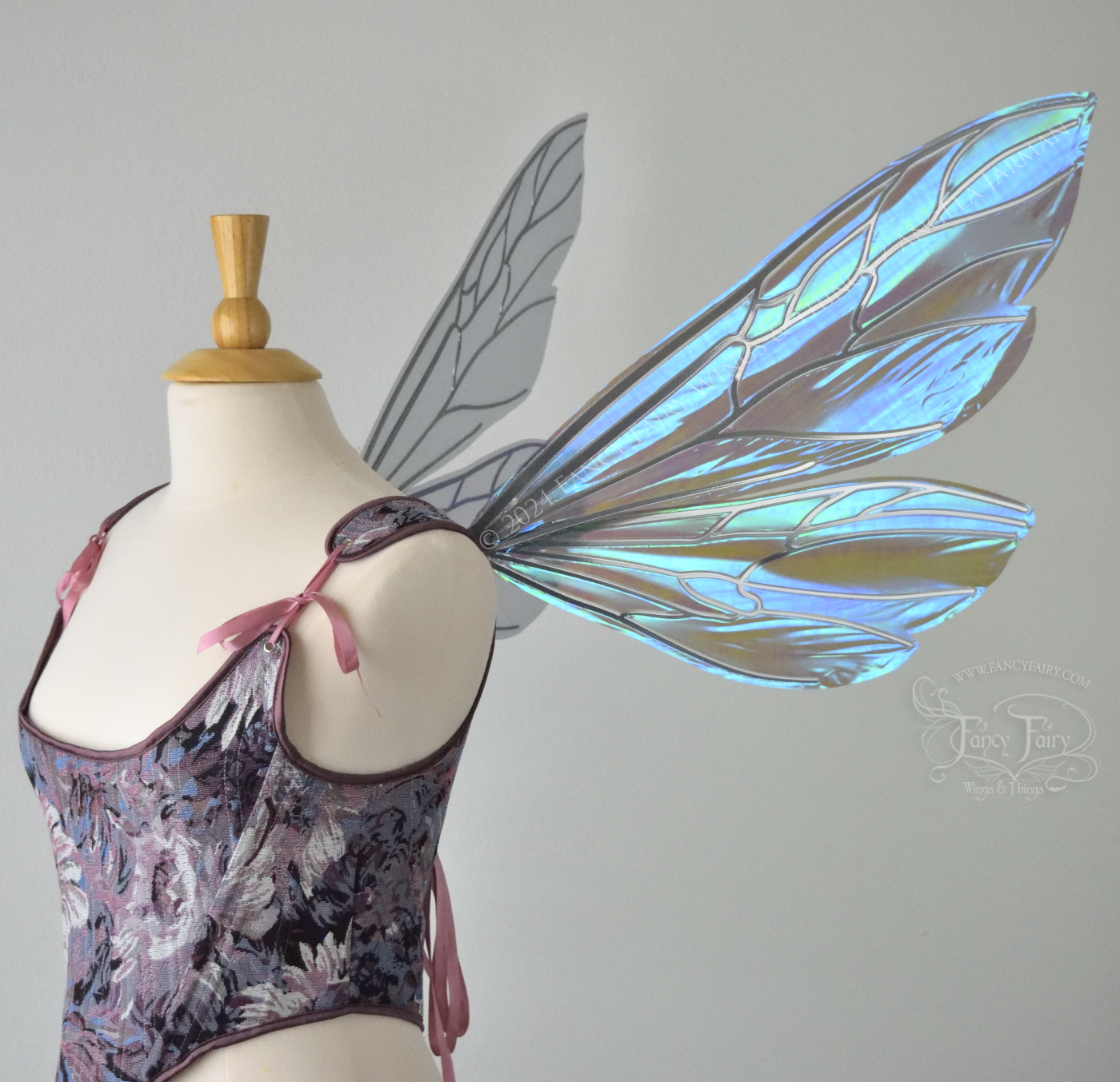 Large fairy wings similar in shape to wasp wings, are iridescent violet / blue with silver veins, right side view