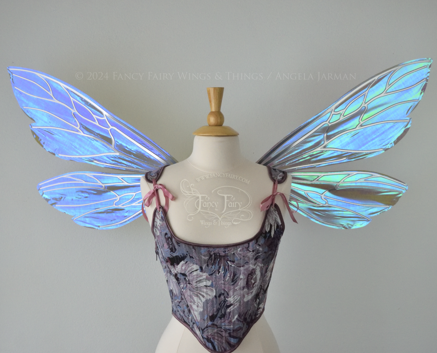 Large fairy wings similar in shape to wasp wings, are iridescent violet / blue with silver veins, front view