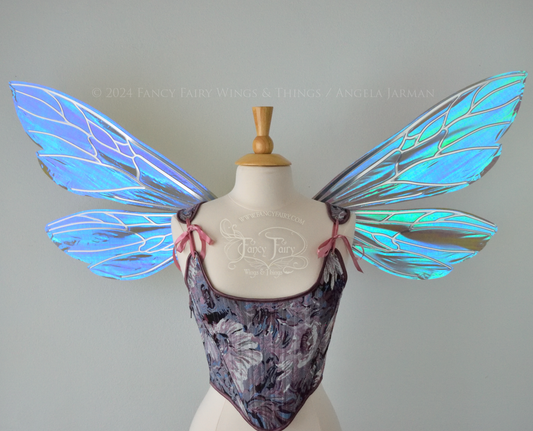 Large fairy wings similar in shape to wasp wings, are iridescent violet / blue with silver veins, front view