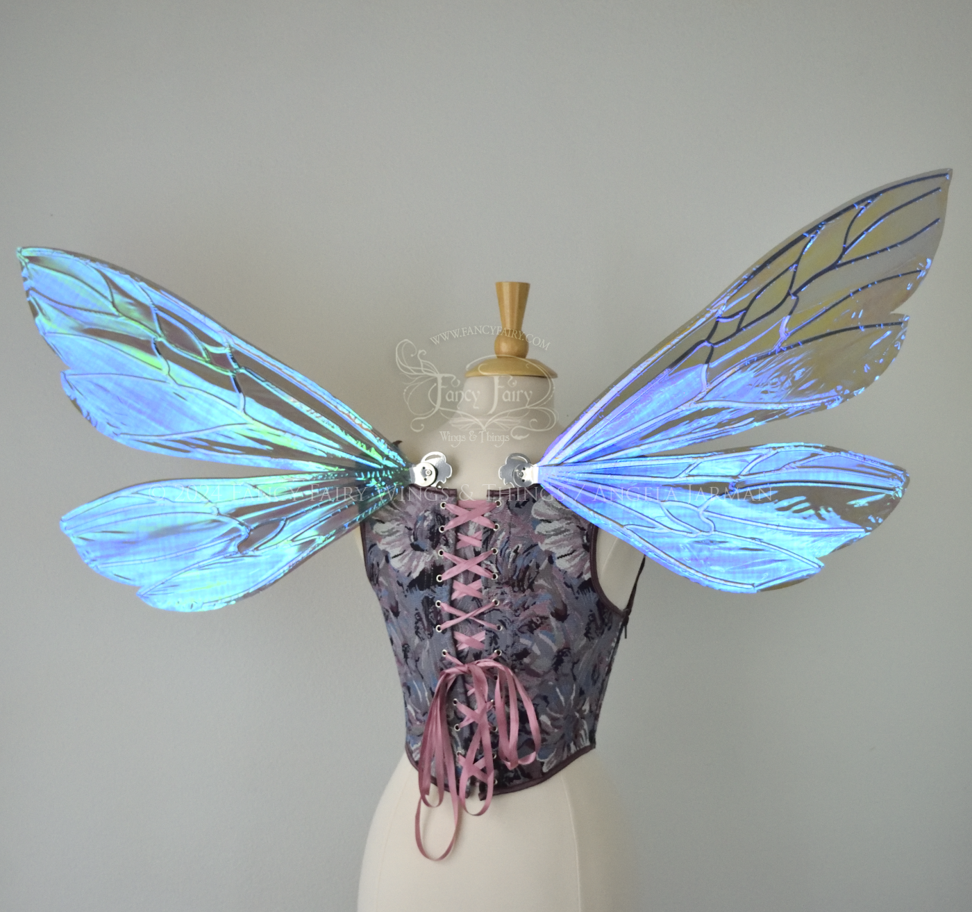 Large fairy wings similar in shape to wasp wings, are iridescent violet / blue with silver veins, back view