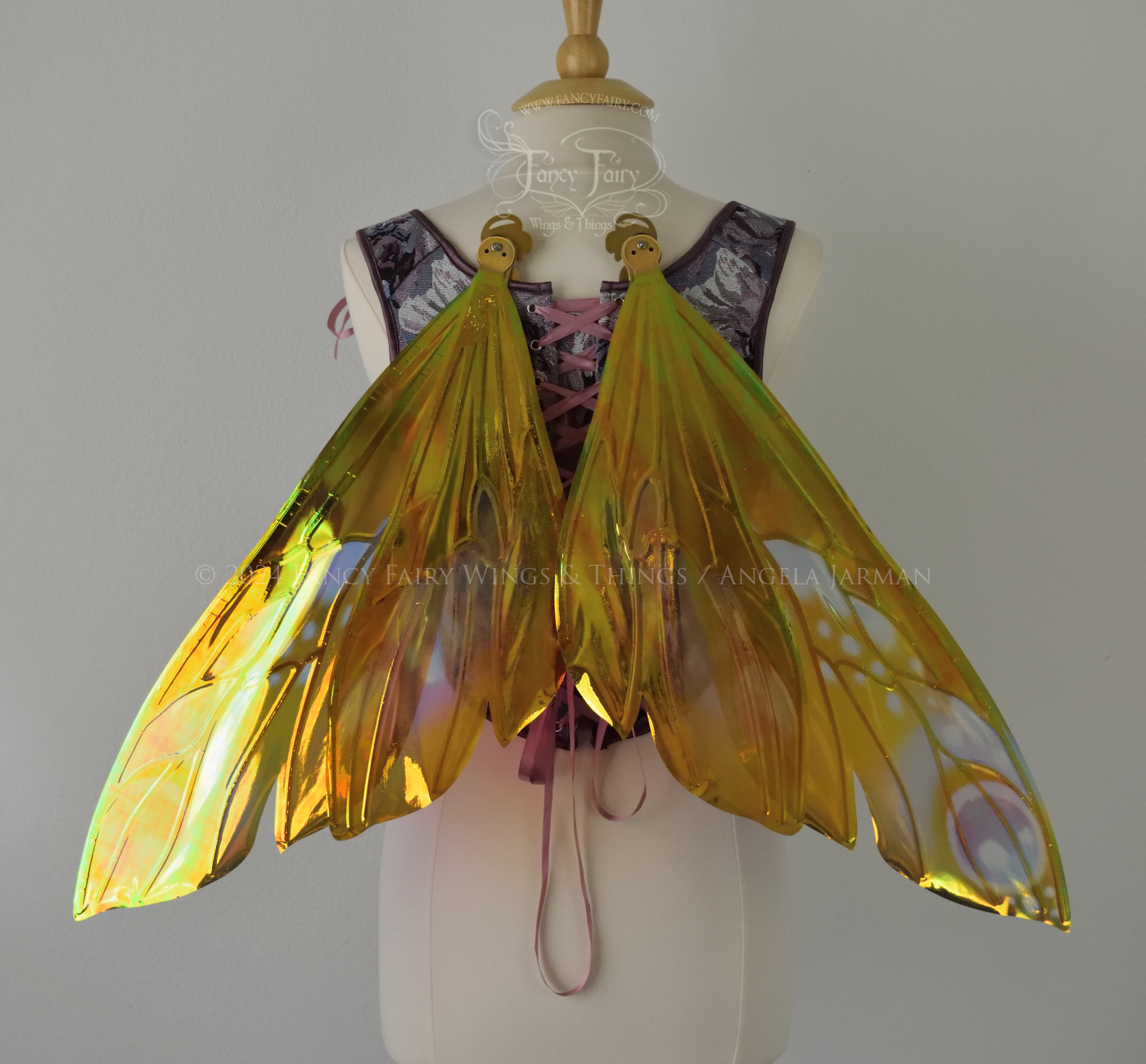 Wasp-shaped iridescent fairy wings in warm orange & rust colors with touches of blue, purple and pink, worn on a dress form, back view, in resting position