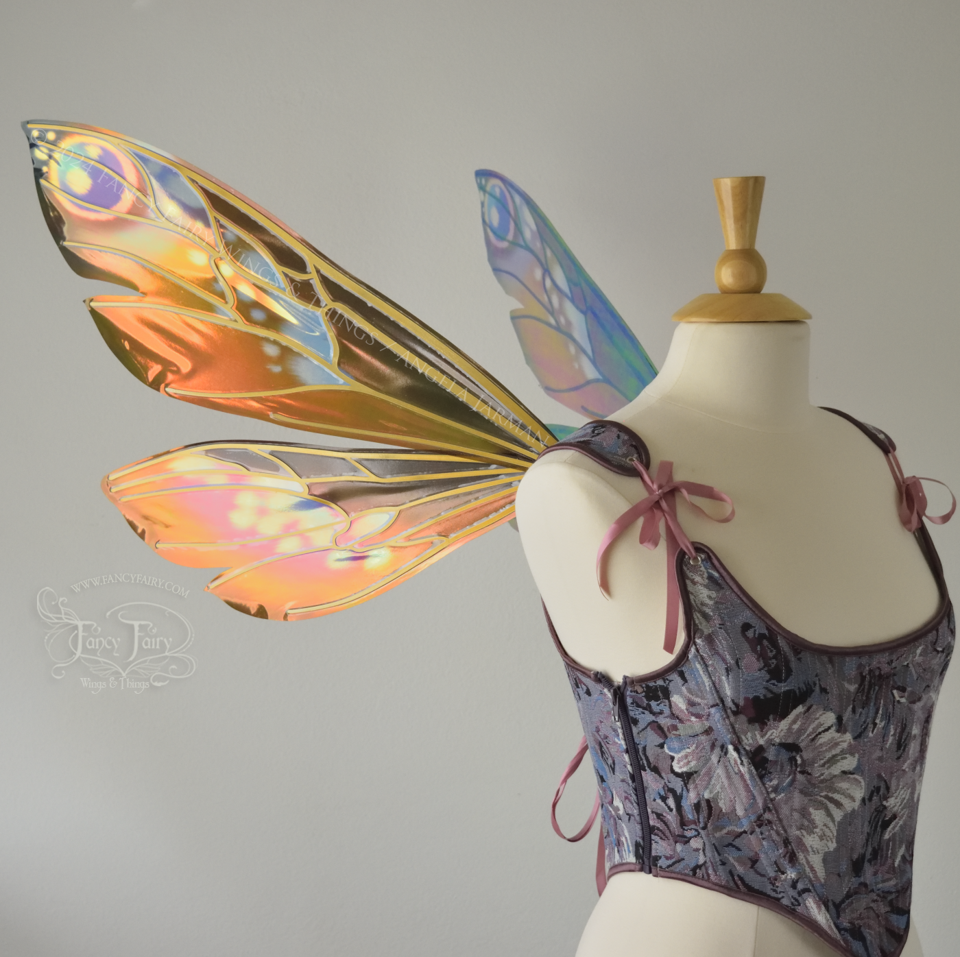 Wasp-shaped iridescent fairy wings in warm orange & rust colors with touches of blue, purple and pink, worn on a dress form, left side view