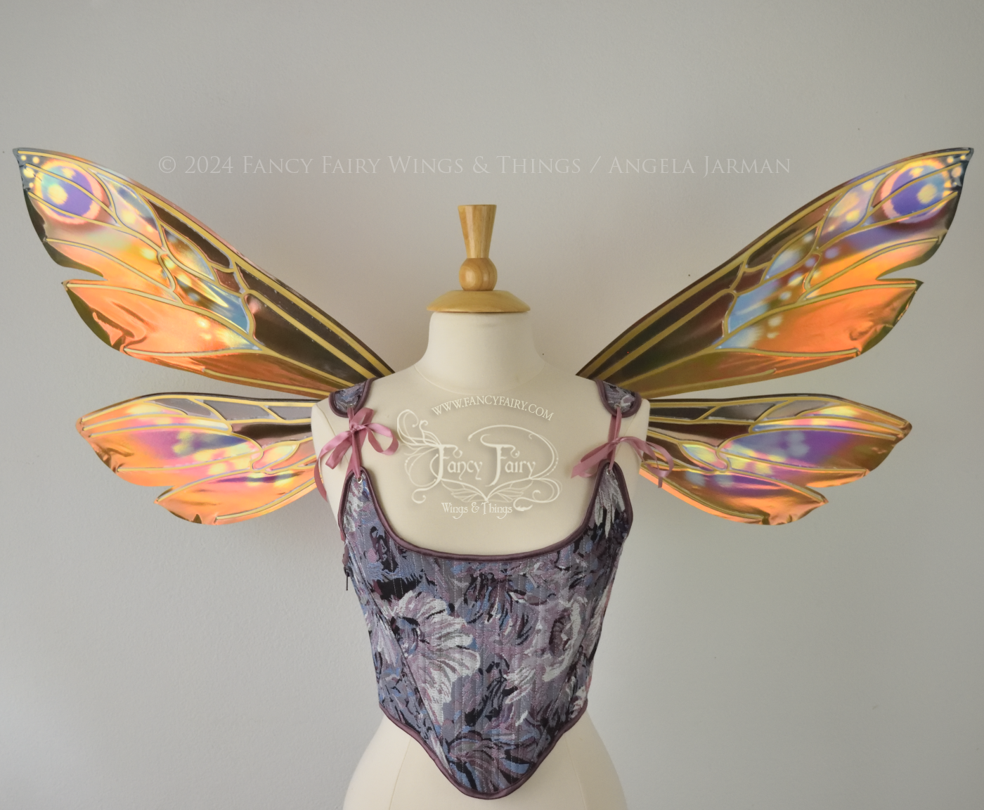 Wasp-shaped iridescent fairy wings in warm orange & rust colors with touches of blue, purple and pink, worn on a dress form, front view