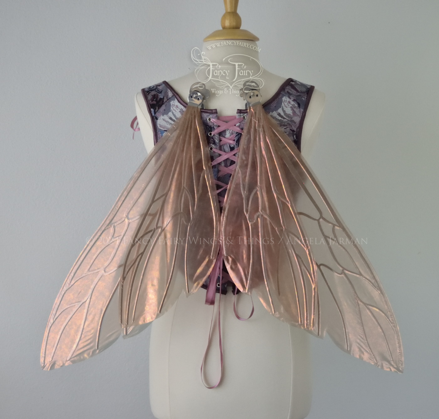 Wasp-shaped fairy wings in iridescent rose gold with silver veins, worn on a dress form, back view, in resting position