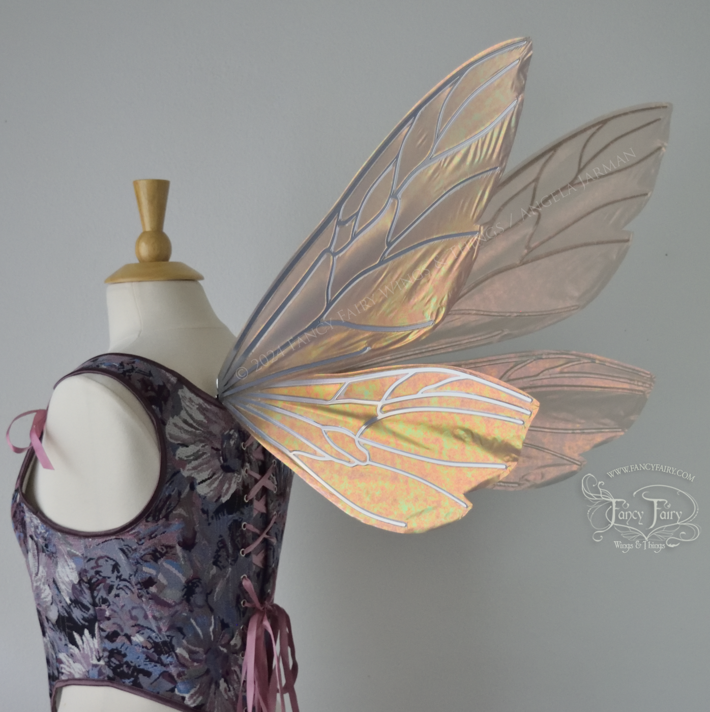 Wasp-shaped fairy wings in iridescent rose gold with silver veins, worn on a dress form, back 3/4 view