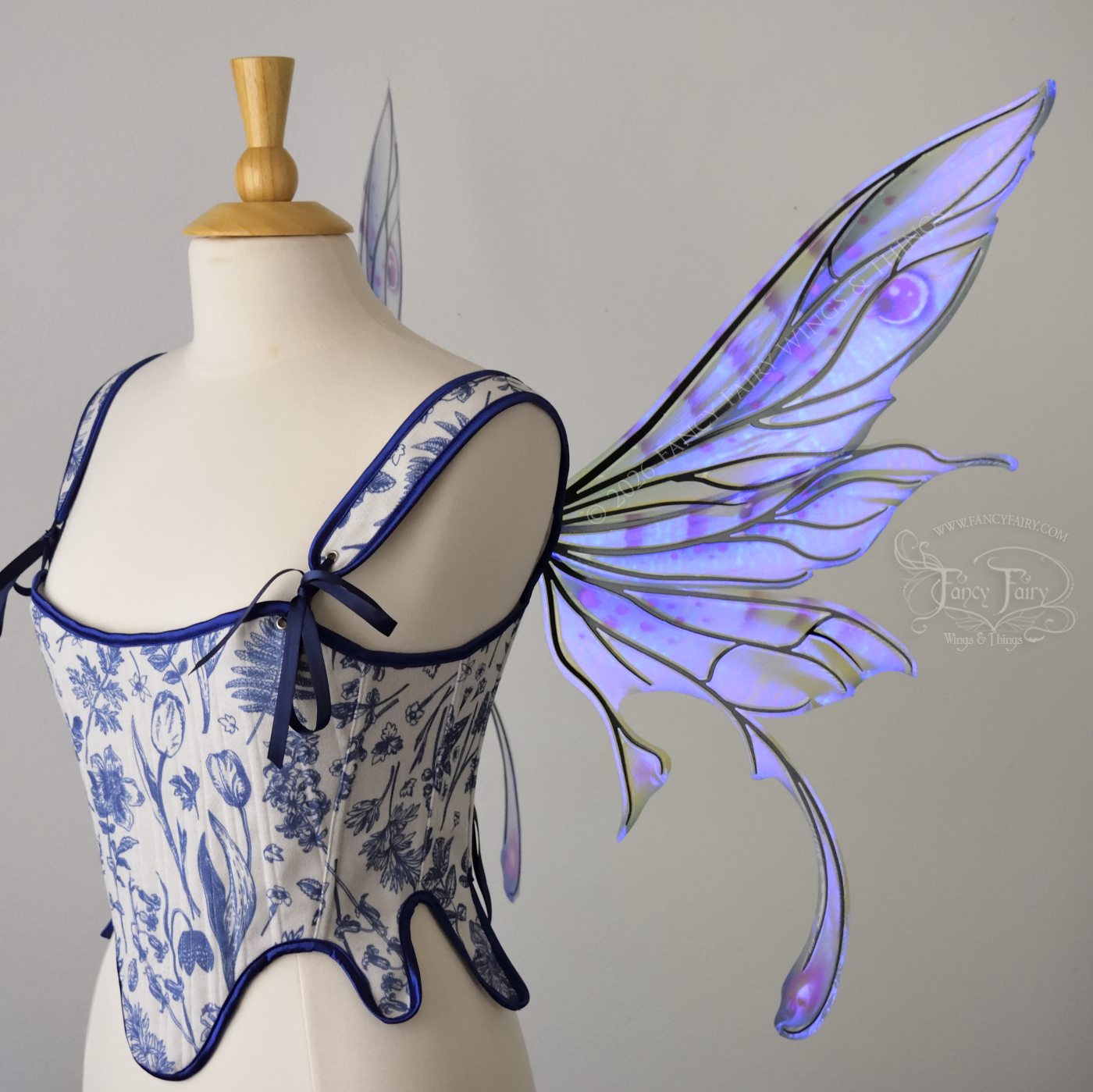 Transparent iridescent blue, fuchsia and violet fairy wings with black veins, 3 panels on each side, bottom panels have tails that curve inward at the bottom. Worn on a dress form, right side view