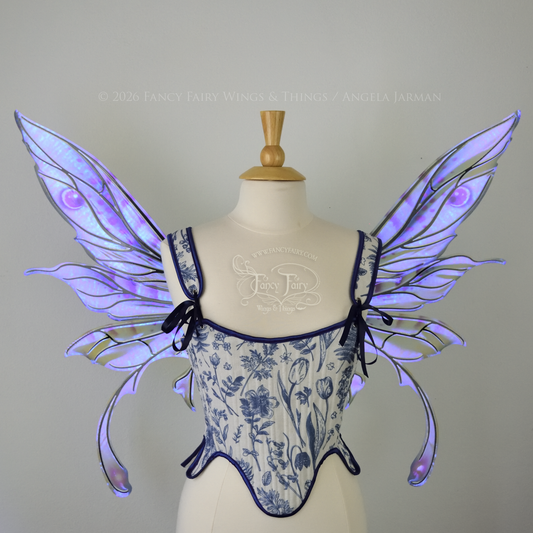 Transparent iridescent blue, fuchsia and violet fairy wings with black veins, 3 panels on each side, bottom panels have tails that curve inward at the bottom. Worn on a dress form, front view