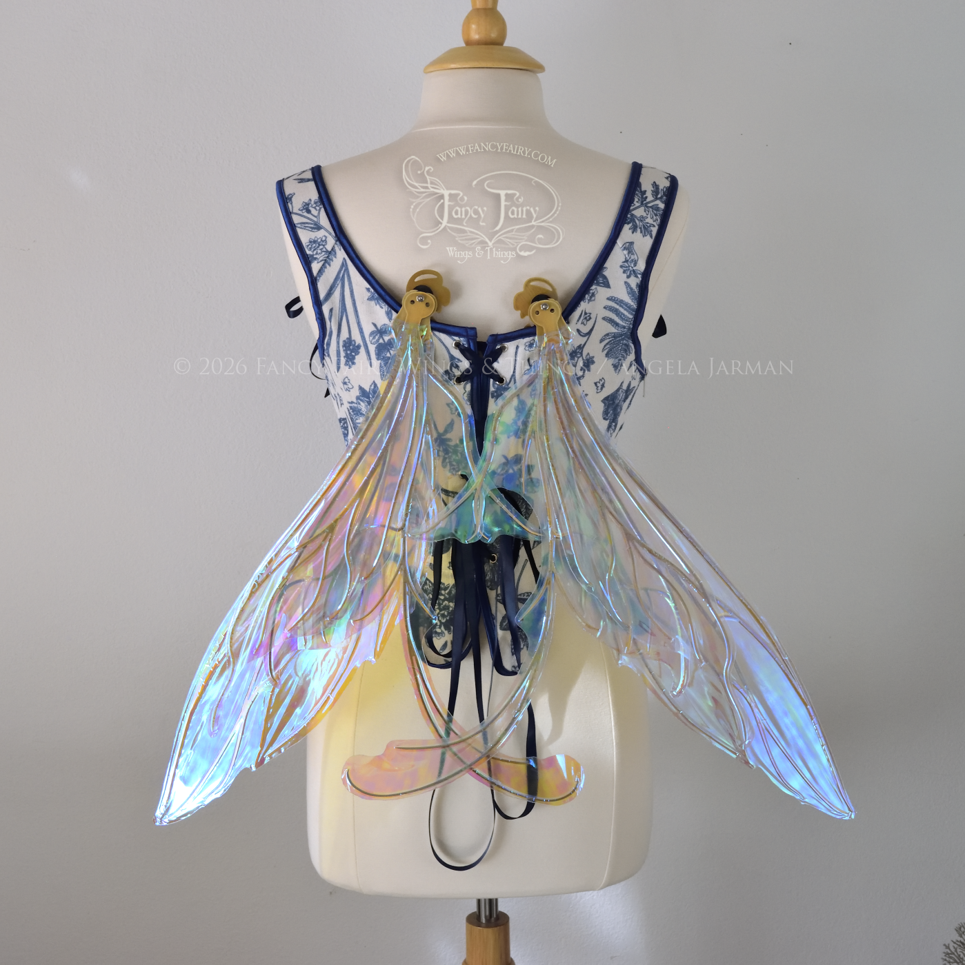 Transparent iridescent blue fairy wings with gold veins, 3 panels on each side, bottom panels have tails that curve inward at the bottom. Worn on a dress form, back view, in resting position