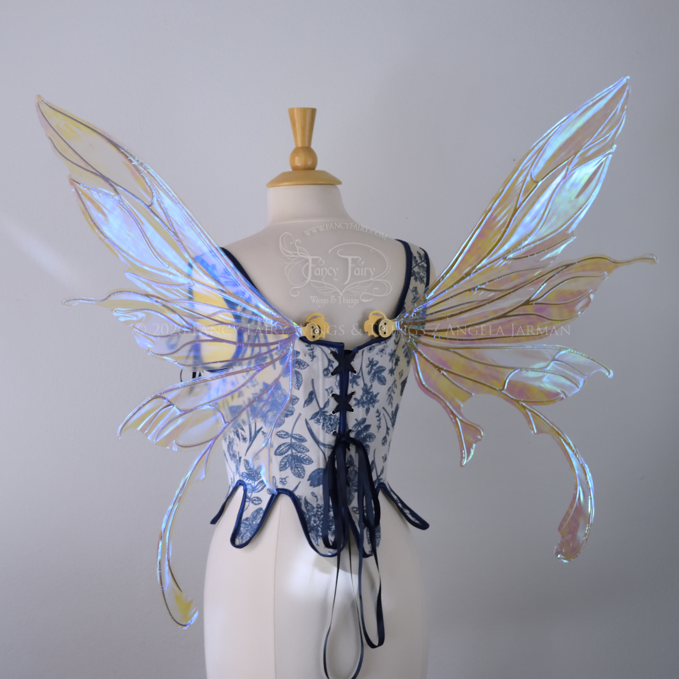 Transparent iridescent blue fairy wings with gold veins, 3 panels on each side, bottom panels have tails that curve inward at the bottom. Worn on a dress form, back view