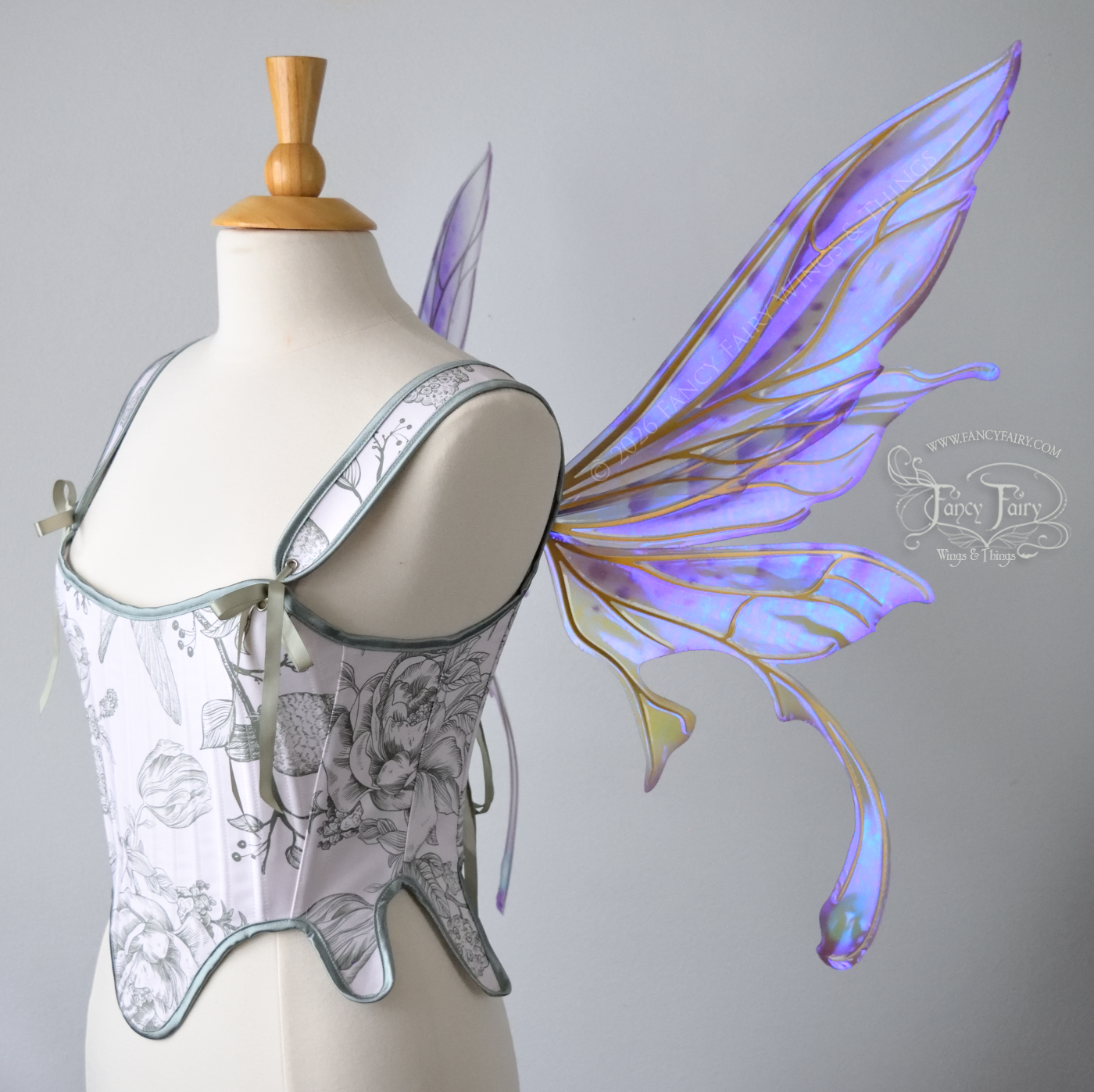 Transparent iridescent violet fairy wings with gold veins, 3 panels on each side, bottom panels have tails that curve inward at the bottom. Worn on a dress form, right side view