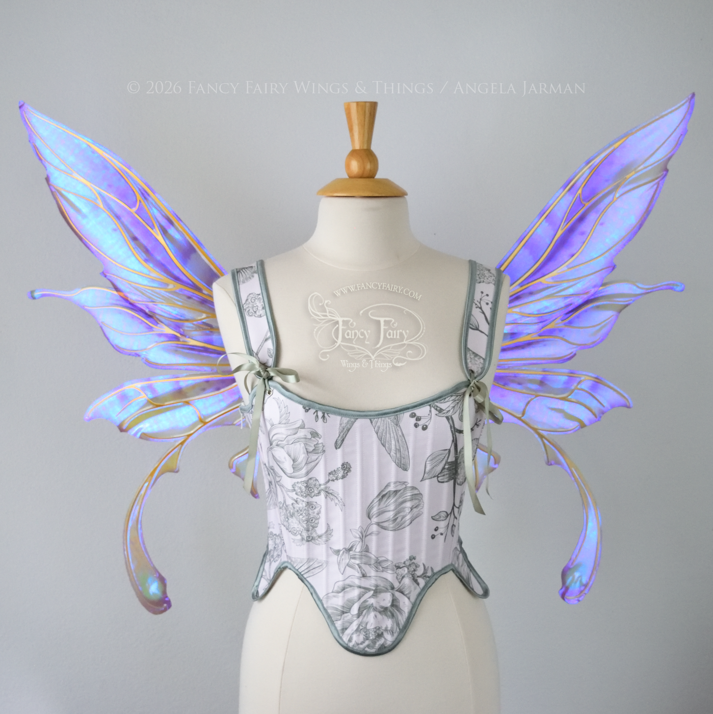 Transparent iridescent violet fairy wings with gold veins, 3 panels on each side, bottom panels have tails that curve inward at the bottom. Worn on a dress form, front view