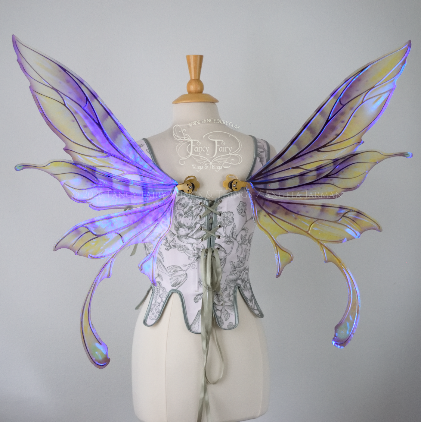 Transparent iridescent violet fairy wings with gold veins, 3 panels on each side, bottom panels have tails that curve inward at the bottom. Worn on a dress form, back view