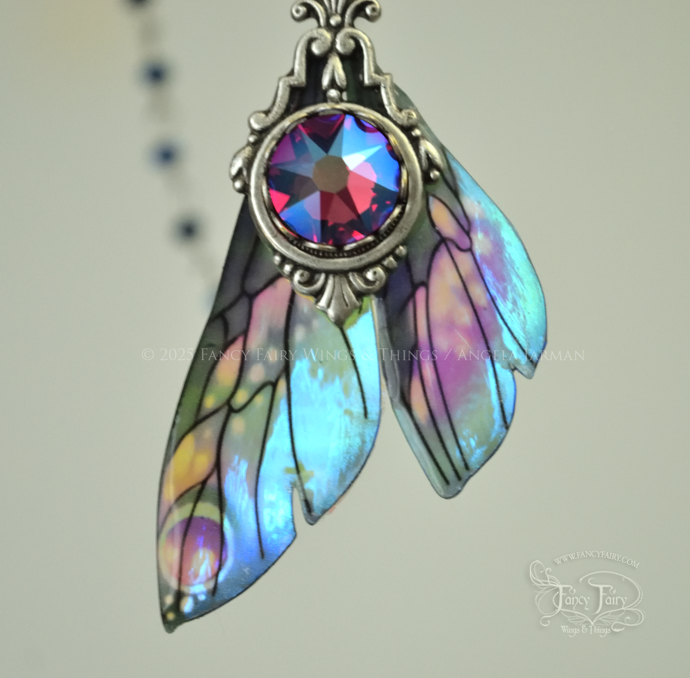 Iridescent fairy wing pendant necklace in teals with pink accents and silver filigree, closeup