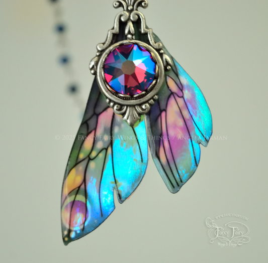 Iridescent fairy wing pendant necklace in teals with pink accents and silver filigree, closeup