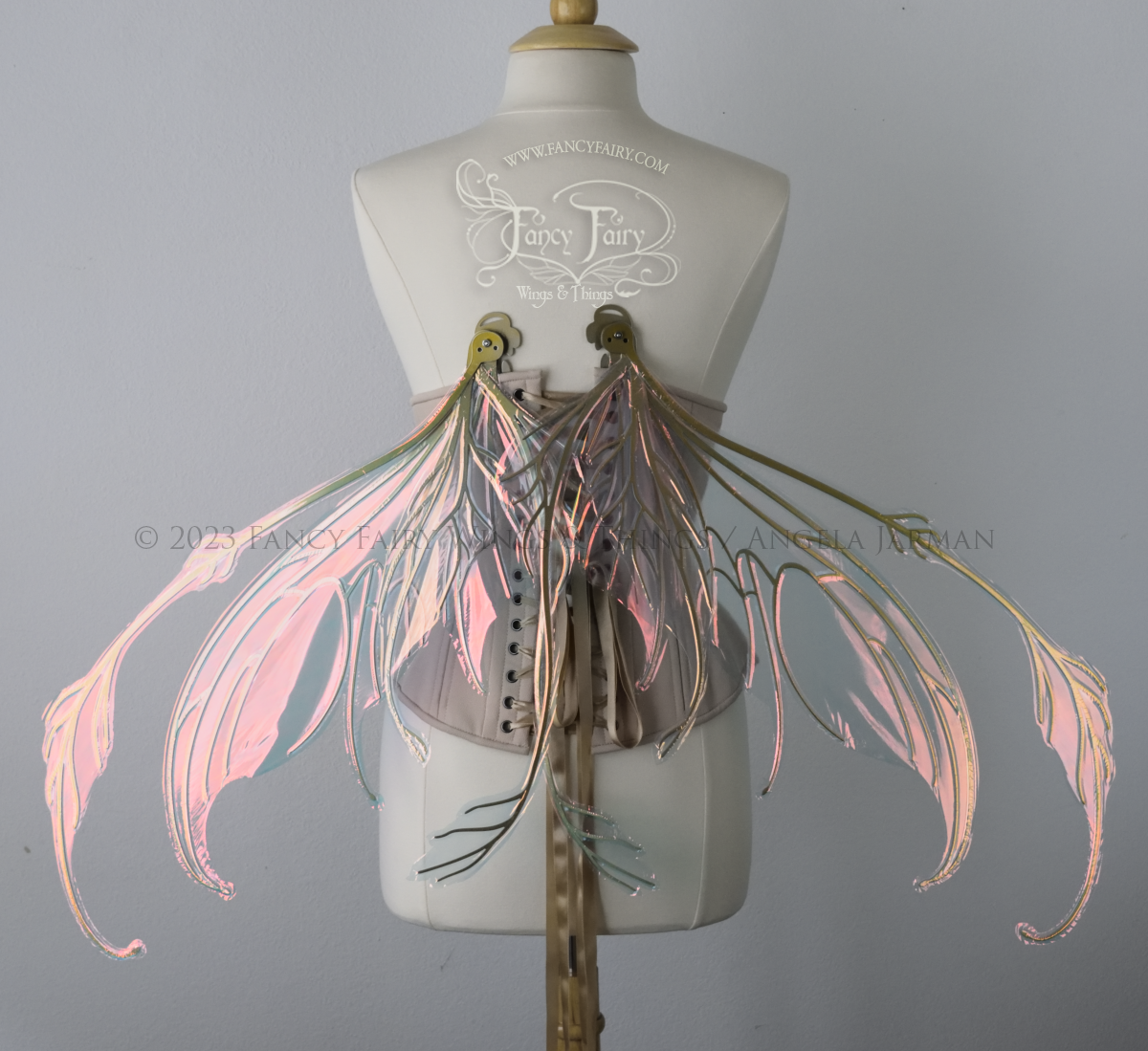 Back view of an ivory dress form wearing an underbust corset & 'Fauna' pinkish iridescent fairy wings with gold veining, in resting position