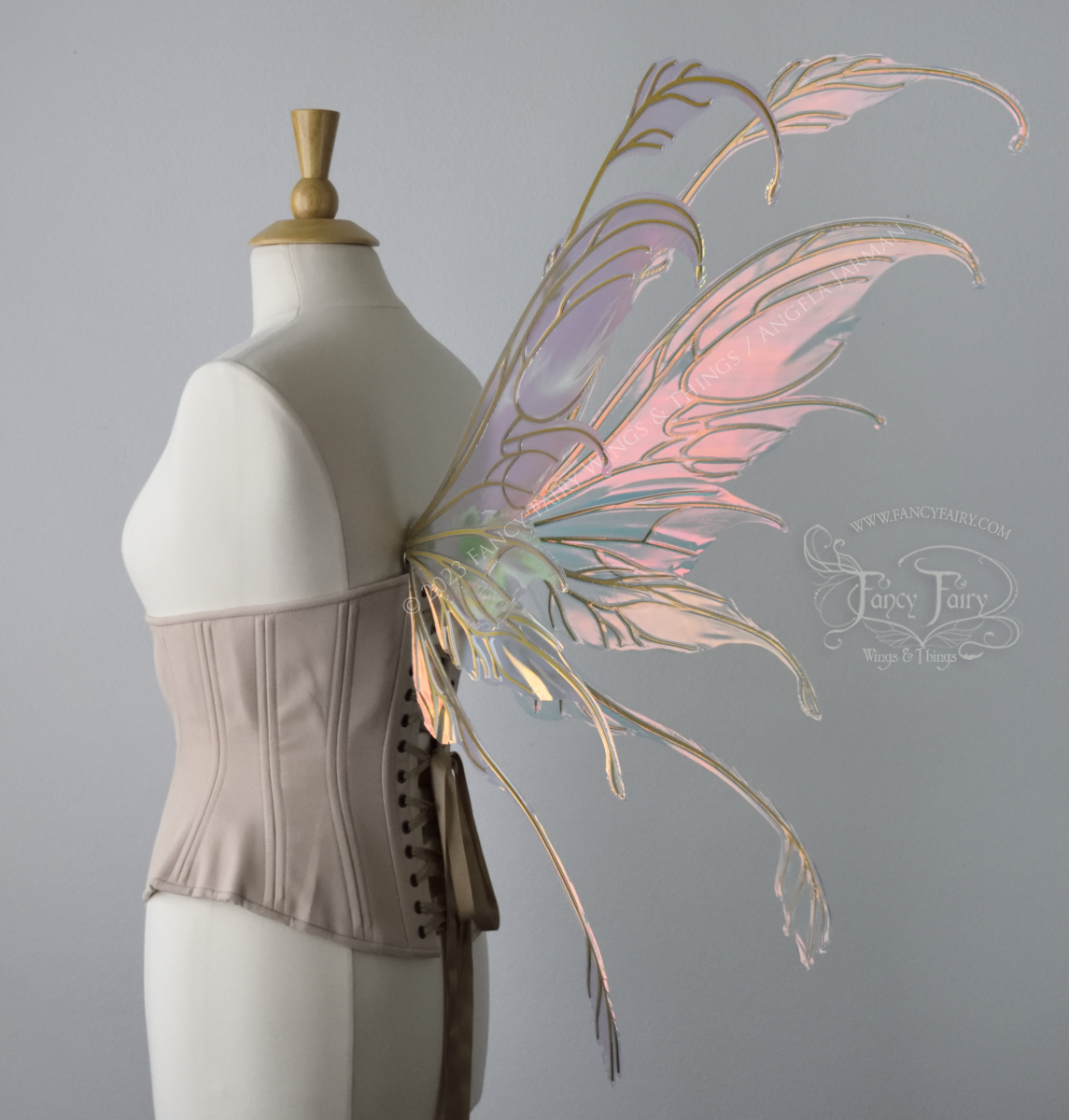 Back 3/4 view of an ivory dress form wearing an underbust corset & 'Fauna' pinkish iridescent fairy wings with gold veining