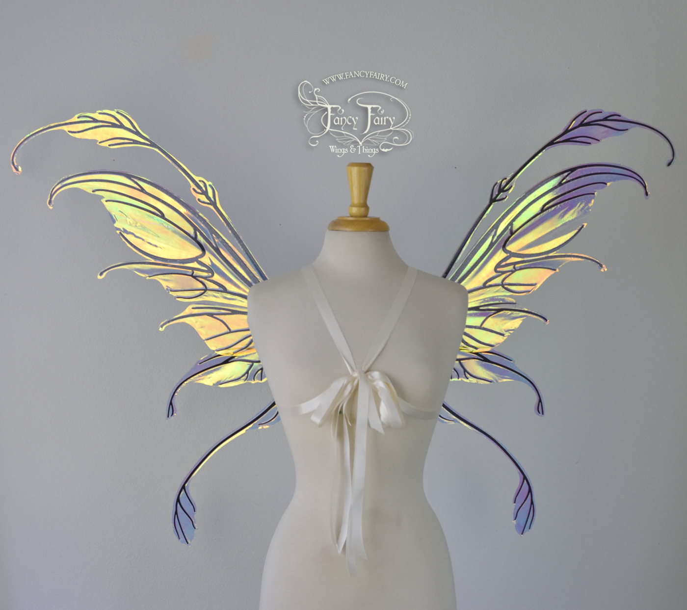 Front view of a dress form wearing 'Fauna' transparent Diamond Fire iridescent fairy wings with downward curved tips, antennae & wispy 'tails', with black veining