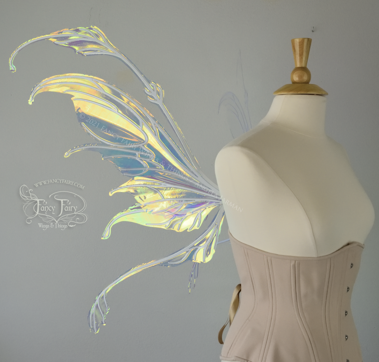 Left side view of a dress form wearing an underbust corset & 'Fauna' transparent iridescent fairy wings with downward curved tips, antennae & wispy 'tails', with white veining