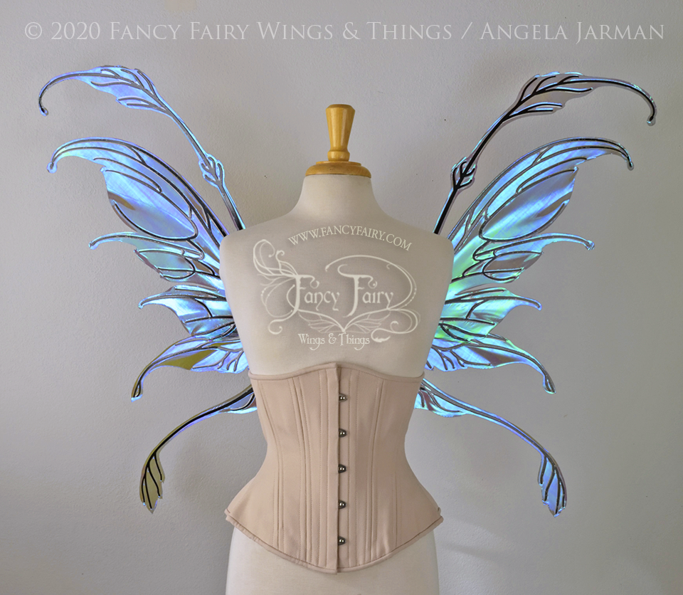 Front view of a dress form wearing an underbust corset & 'Fauna' transparent purple / blue iridescent fairy wings with downward curved tips, antennae & wispy 'tails', with black veining