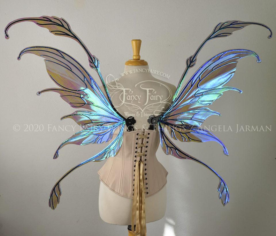 Back view of a dress form wearing an underbust corset & 'Fauna' transparent purple / blue iridescent fairy wings with downward curved tips, antennae & wispy 'tails', with black veining