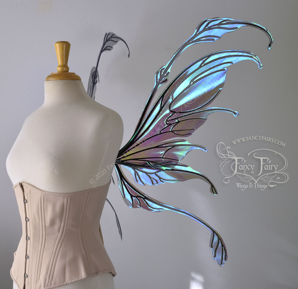 Right side view of a dress form wearing an underbust corset & 'Fauna' transparent purple / blue iridescent fairy wings with downward curved tips, antennae & wispy 'tails', with black veining