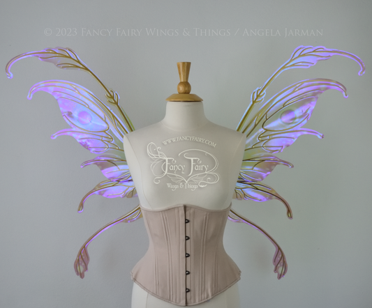 Front view of a dress form wearing an underbust corset & 'Fauna' transparent pink, violet & green iridescent fairy wings with downward curved tips, antennae & wispy 'tails', with gold veining