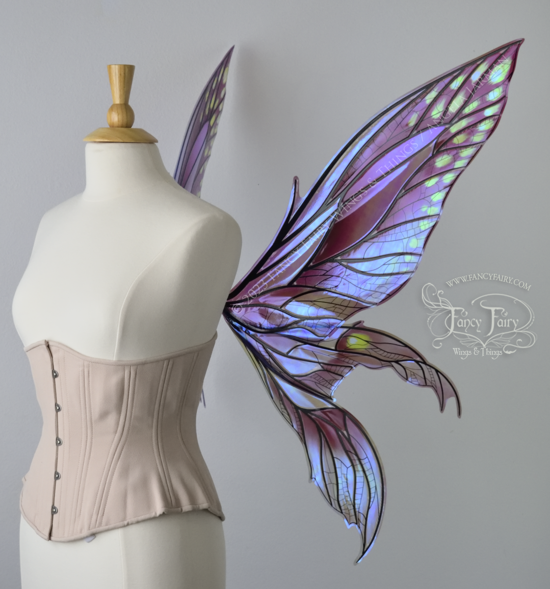 Right side view of dress form wearing large plum iridescent fairy wings with green accents. 3 pointed panels each side, detailed black veins