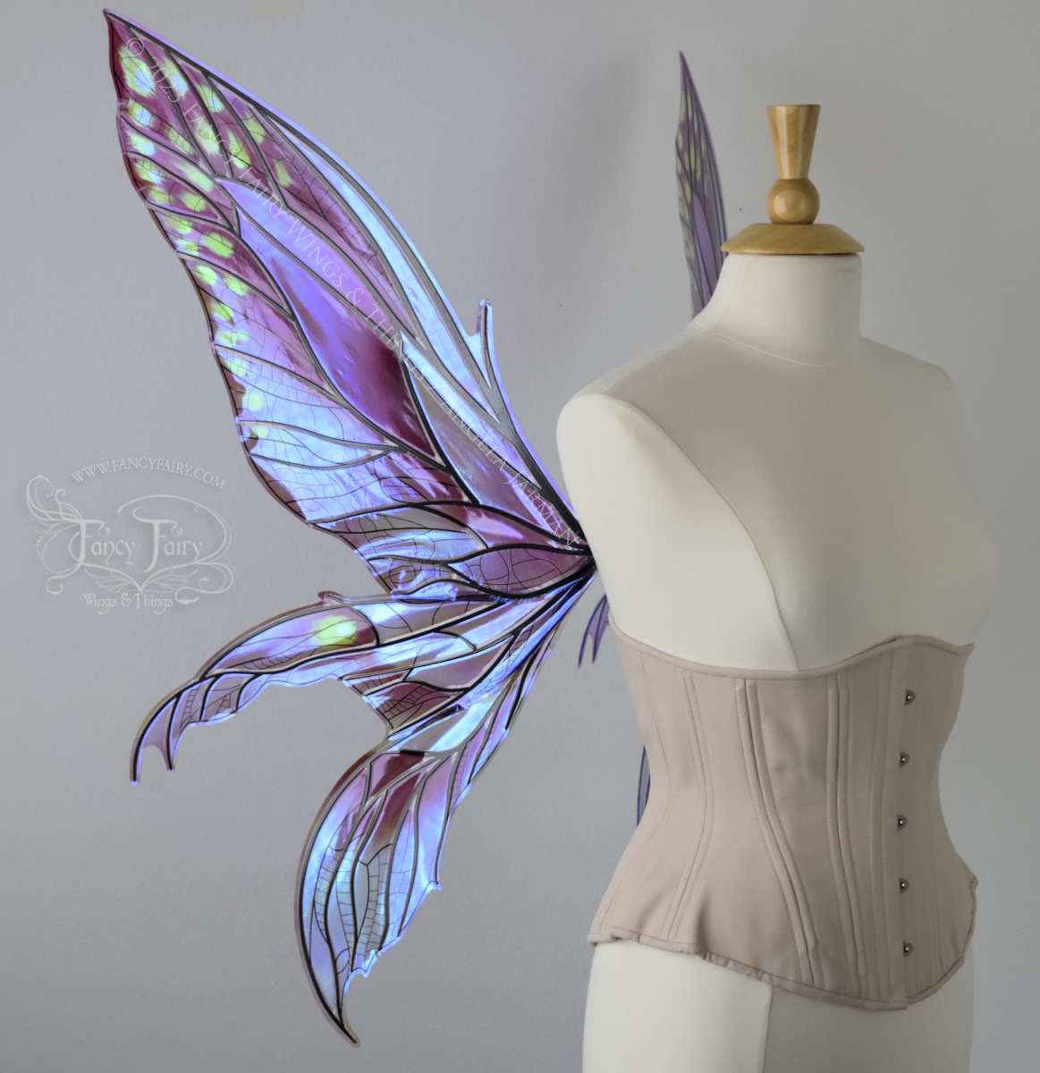 Left view of dress form wearing large plum iridescent fairy wings with green accents. 3 pointed panels each side, detailed black veins