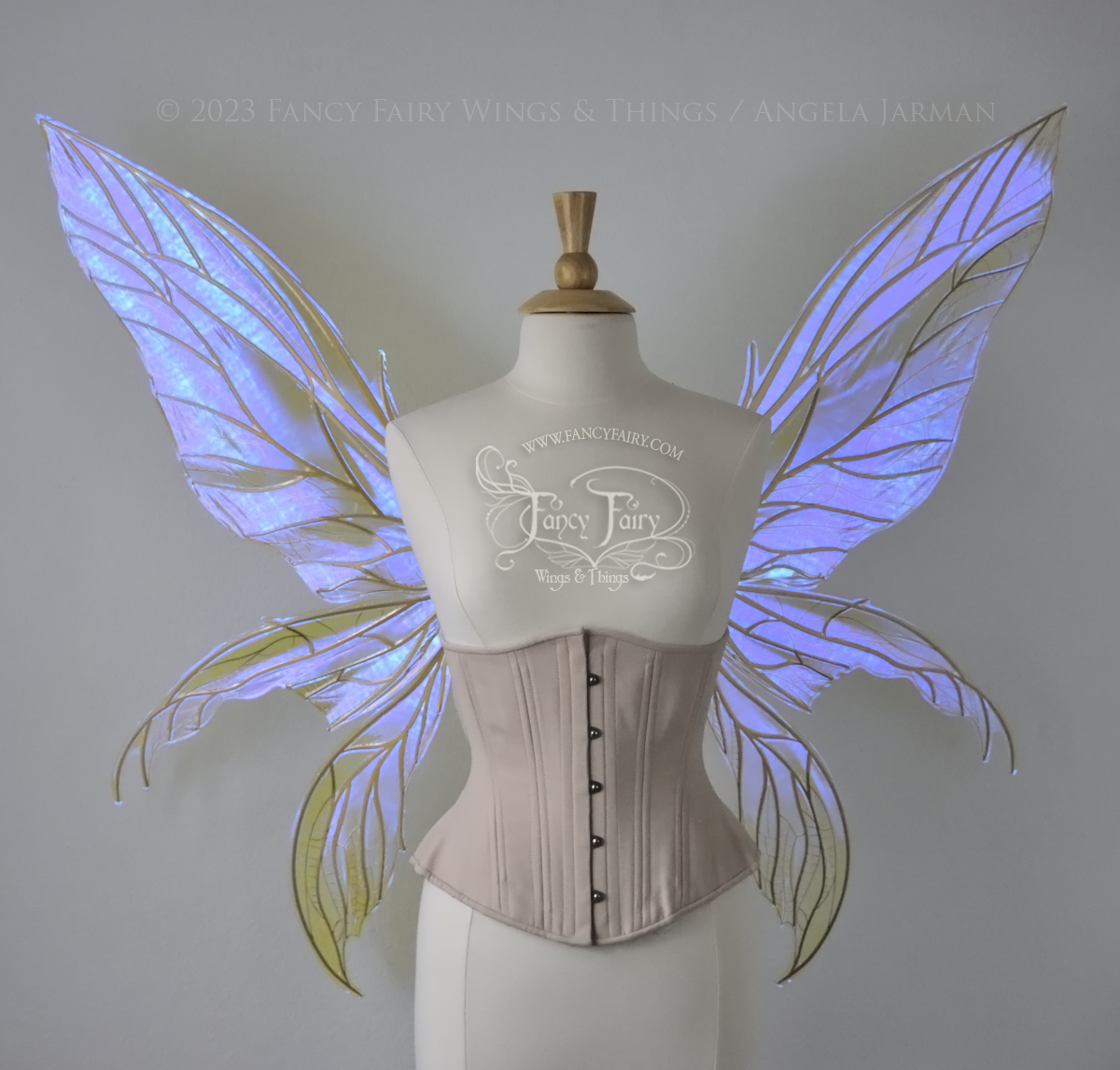 Front view of an ivory dress form wearing an alabaster underbust corset & large violet iridescent fairy wings. Upper panels are elongated with pointed tips, 2 lower panels curve downward, lots of thin vein detail in gold