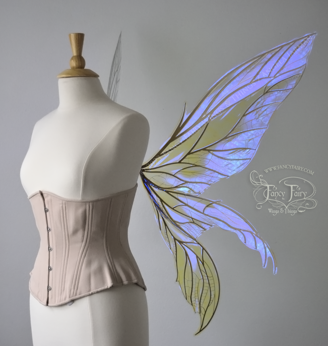 Right side view of an ivory dress form wearing an alabaster underbust corset & large violet iridescent fairy wings. Upper panels are elongated with pointed tips, 2 lower panels curve downward, lots of thin vein detail in gold
