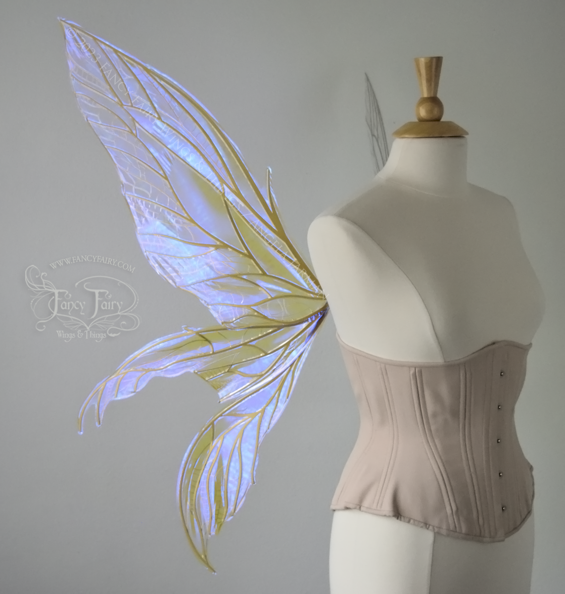 Left side view of an ivory dress form wearing an alabaster underbust corset & large violet iridescent fairy wings. Upper panels are elongated with pointed tips, 2 lower panels curve downward, lots of thin vein detail in gold