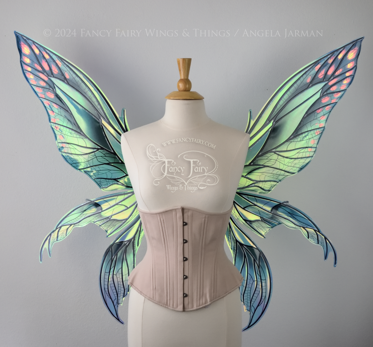 Front view of large green and blue iridescent fairy wings with 3 panels on each side, pointed tips, lots of vein detail, worn on a dress form.