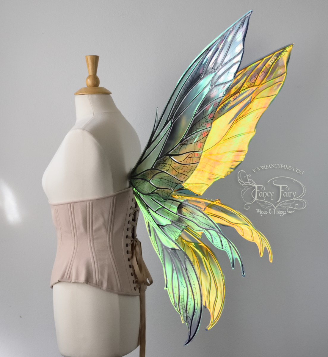 Back 3/4 view of large green & blue iridescent fairy wings with 3 panels on each side, pointed tips, lots of veins, worn on a dress form