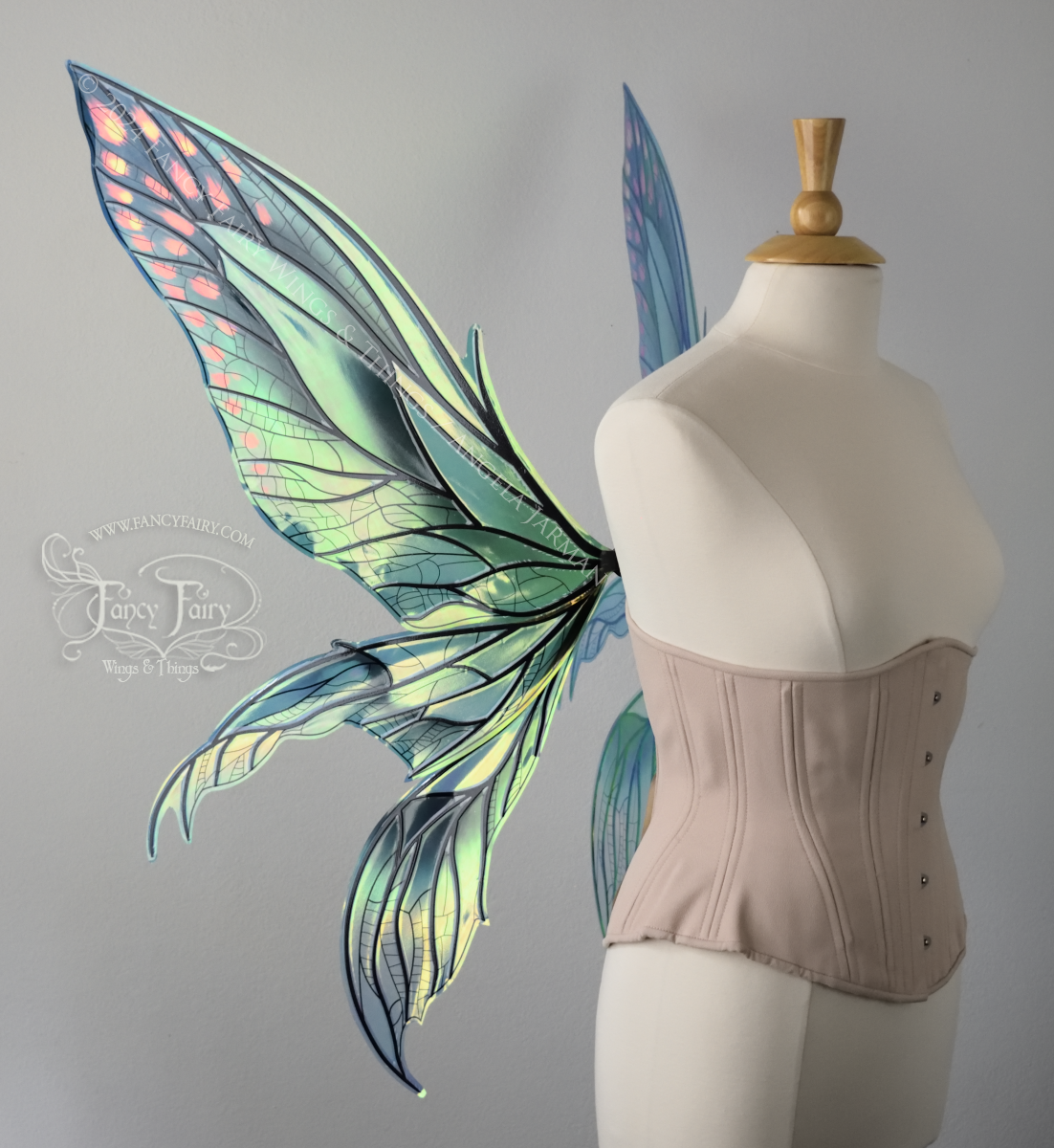 Left side view of large green & blue iridescent fairy wings with 3 panels on each side, pointed tips, lots of veins, worn on a dress form