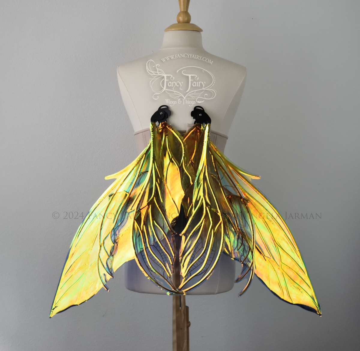 Back view of large green & blue iridescent fairy wings with 3 panels on each side, pointed tips, lots of veins, worn on a dress form, in resting position