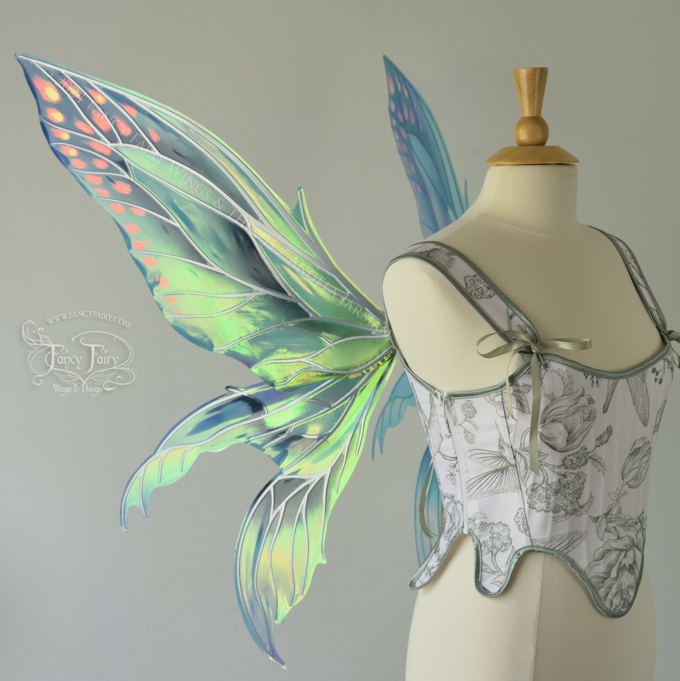 Large 'Fayette' large iridescent blue and green fairy wings with 3 panels on each side, pink dots near the upper panel tips, & silver veins, worn on a dress form, left side view