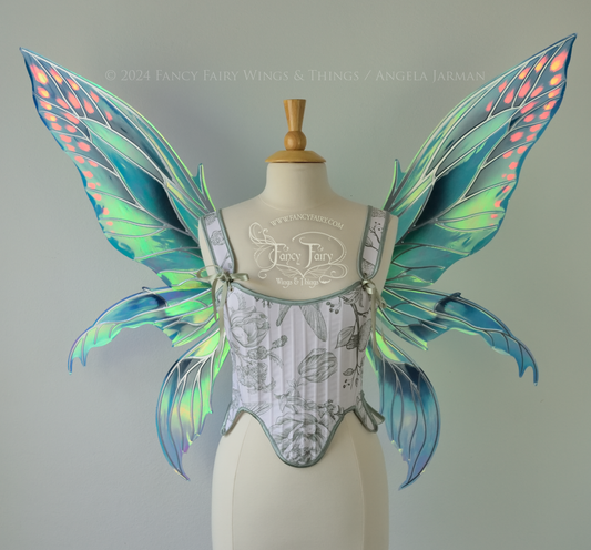 Large 'Fayette' large iridescent blue and green fairy wings with 3 panels on each side, pink dots near the upper panel tips, & silver veins, worn on a dress form, front view