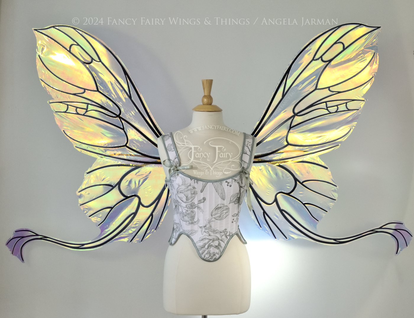 Gigantic transparent & yellow/green/orange iridescent butterfly shaped fairy wings with black veins and 'tails' that curve out from the bottom panels, worn on a dress form
