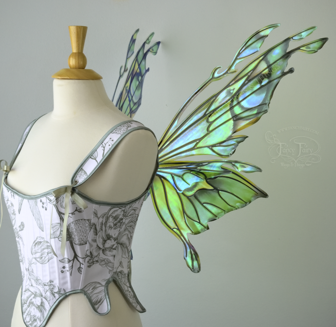 Iridescent green, blue and black fairy wings with antennae and small appendages sticking out from the tips, worn on a dress form, right side view
