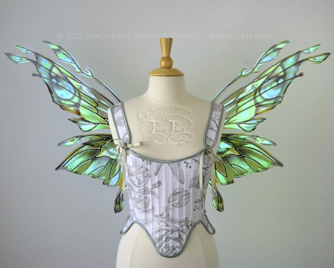 Iridescent green, blue and black fairy wings with antennae and small appendages sticking out from the tips, worn on a dress form, front view