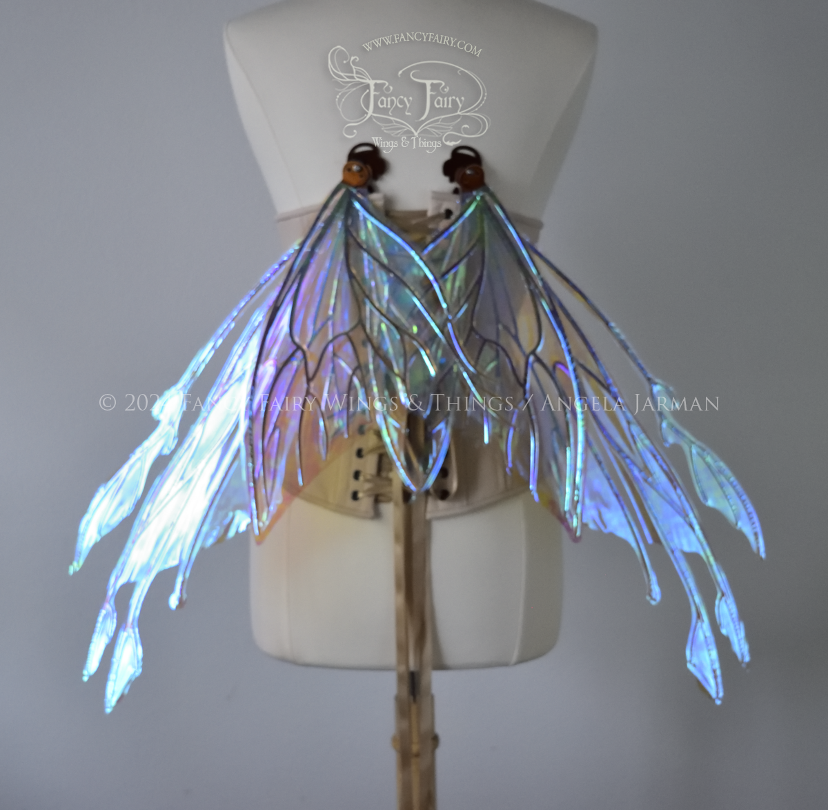 Large blue green iridescent fairy wings with copper veins worn with an alabaster corset on a dress form, back view, in resting position