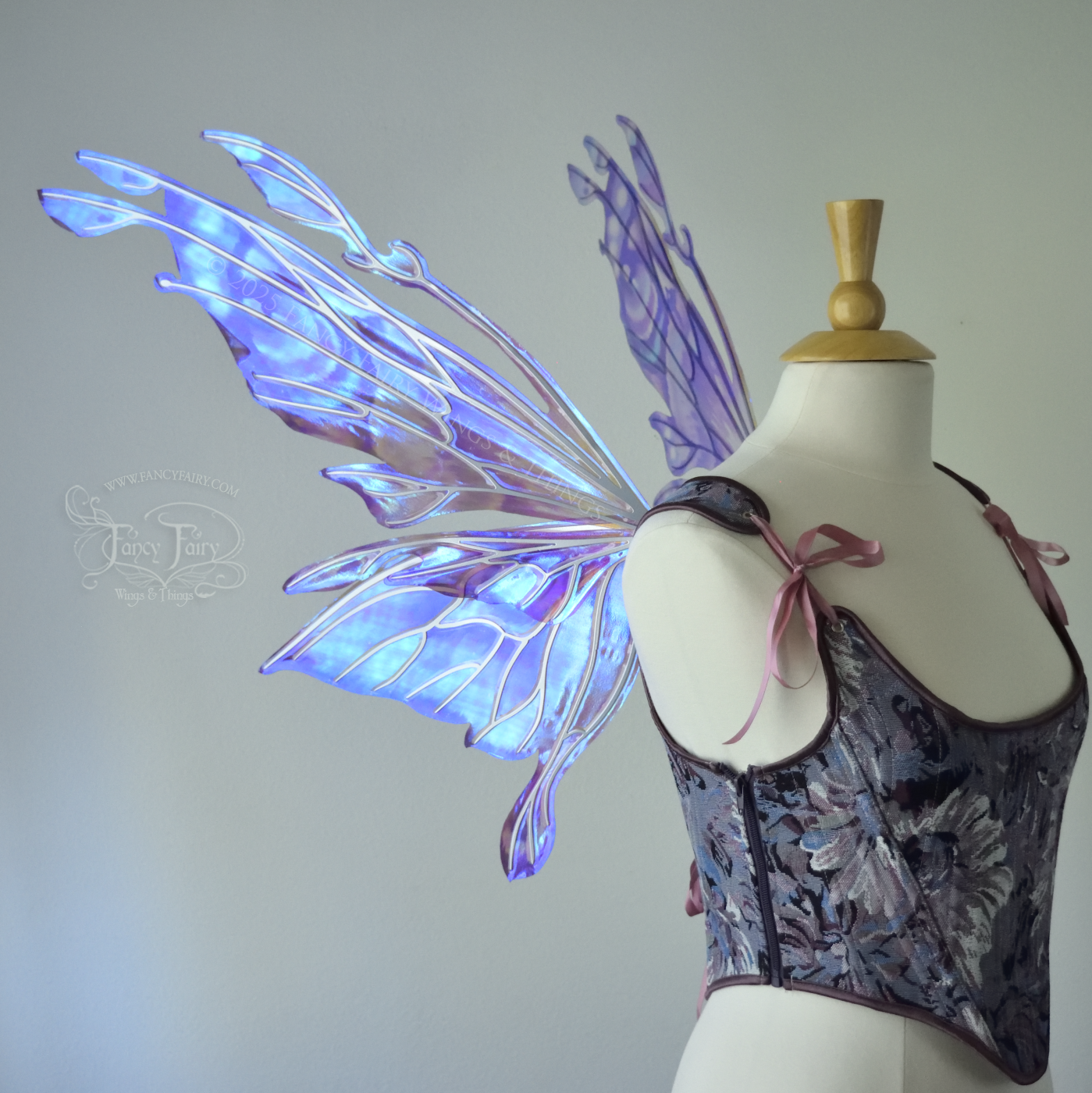 Iridescent lavender, light blue and pink fairy wings with antennae and small appendages sticking out from the tips, the veins are silver, worn on a dress form, left side view