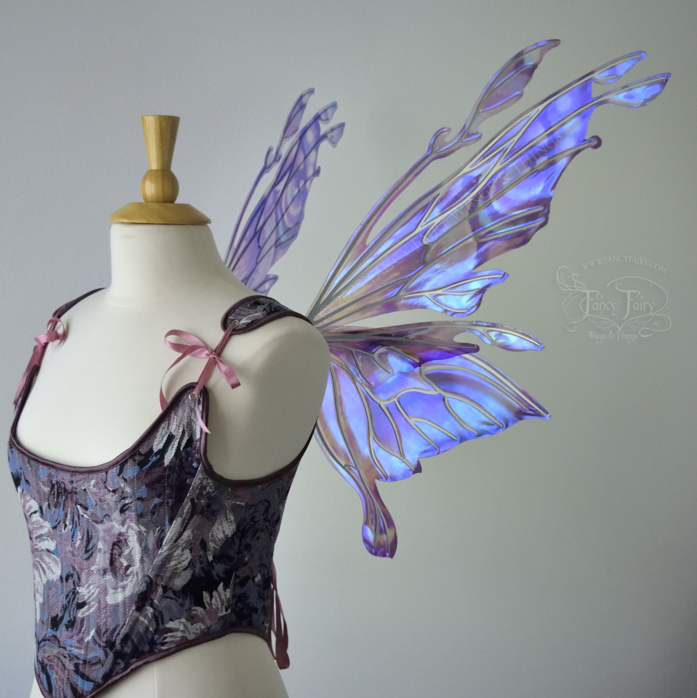 Iridescent lavender, light blue and pink fairy wings with antennae and small appendages sticking out from the tips, the veins are silver, worn on a dress form, right side view