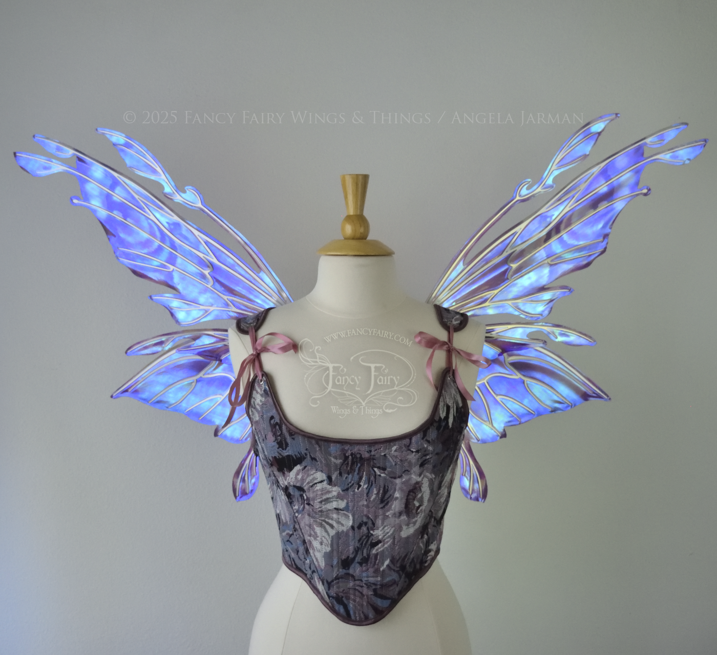 Iridescent lavender, light blue and pink fairy wings with antennae and small appendages sticking out from the tips, the veins are silver, worn on a dress form, front view