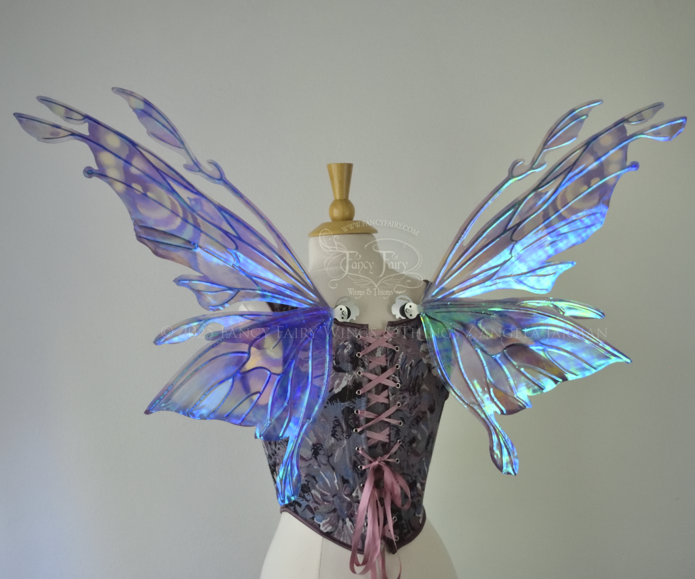 Iridescent lavender, light blue and pink fairy wings with antennae and small appendages sticking out from the tips, the veins are silver, worn on a dress form, back view