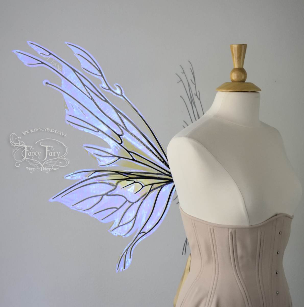 Left side view of an ivory dress form wearing an alabaster underbust corset & large violet iridescent fairy wings with elongated upper panels with petal like appendages at the tips & antennae, the veins are black