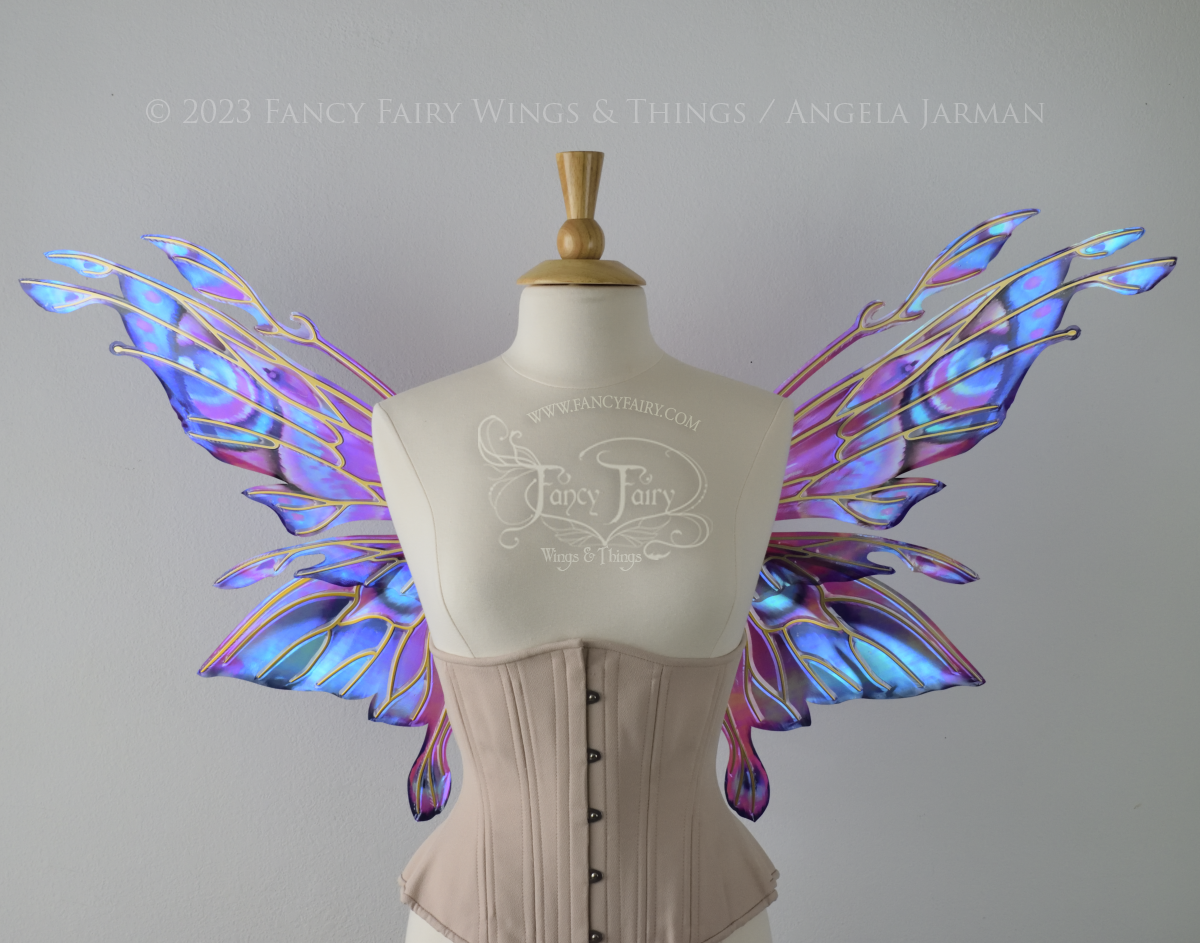 Front view of an ivory dress form wearing an underbust corset & 'Goblin Princess' magenta & blue painted iridescent wings w/ gold veins 