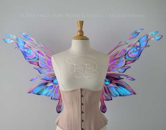 Front view of an ivory dress form wearing an underbust corset & 'Goblin Princess' magenta & blue painted iridescent wings w/ gold veins 
