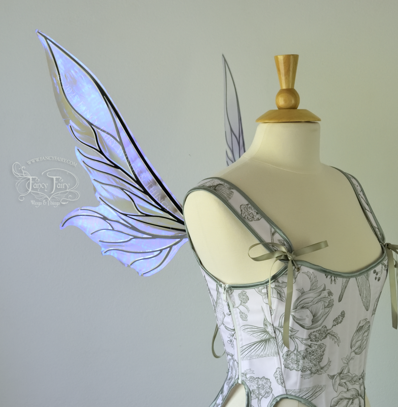 Iridescent & transparent violet fairy wings with elongated pointy upper panels and small leaf like lower panels, with black veins, left side view